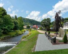 Szczyrk – zagospodarowany bulwar wzdłuż potoku, ścieżka spacerowa i zabudowa apartamentowa na tle gór Beskidu Śląskiego