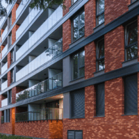 Nowoczesny budynek mieszkalny z elewacją z czerwonej cegły ceramicznej i przeszklonymi balkonami