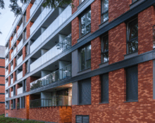 Nowoczesny budynek mieszkalny z elewacją z czerwonej cegły ceramicznej i przeszklonymi balkonami