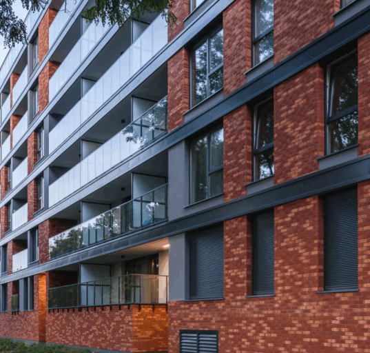 Nowoczesny budynek mieszkalny z elewacją z czerwonej cegły ceramicznej i przeszklonymi balkonami