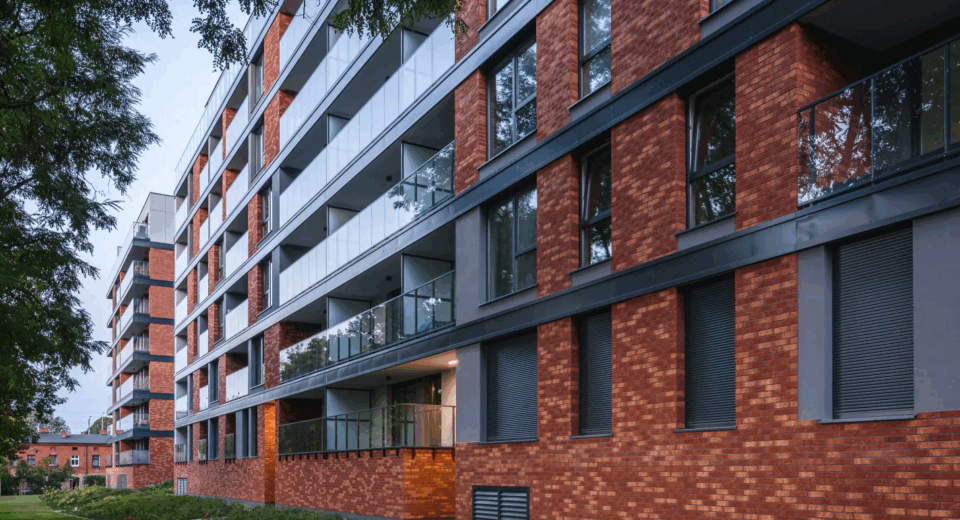 Nowoczesny budynek mieszkalny z elewacją z czerwonej cegły ceramicznej i przeszklonymi balkonami