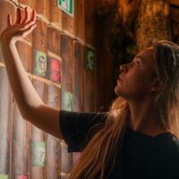Nastolatka rozwiązuje zagadki w escape roomie — szuka wskazówek na drewnianej ścianie