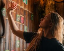 Nastolatka rozwiązuje zagadki w escape roomie — szuka wskazówek na drewnianej ścianie